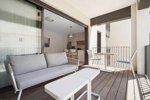 a living room with a couch and a table on a balcony at Mamad New With Terrace Next To Park By Feelhome in Tel Aviv