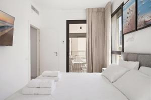 a white bedroom with a large bed with two pillows at Mamad New With Terrace Next To Park By Feelhome in Tel Aviv