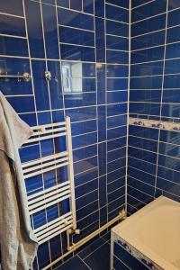a blue tiled bathroom with a shower with a towel at Vibe Apartament 17 in Galaţi +6 photos