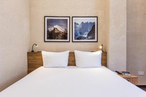 a bed in a hotel room with two pictures on the wall at TAU 28 Hotel in Almaty