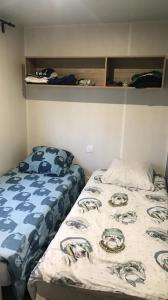two beds in a small room with a bedskirtspectspectssenalsenalsenalsenal at Camping 2 étoiles - Piscine - ccbgcid in Belloc