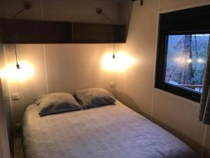a bedroom with a bed with two pillows and a window at Camping 2 étoiles - Piscine - ccbgcid in Belloc