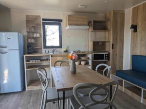 a kitchen with a table and chairs and a refrigerator at Camping 2 étoiles - Piscine - ccbgcid in Belloc +6 photos