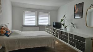 a white bedroom with a bed and a television at Ferienwohnungen Walsrode in Walsrode