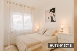 een witte slaapkamer met een bed en een raam bij Blanco Vinyet in Sitges