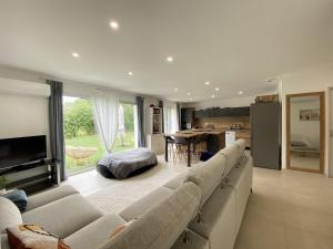 a living room with a large couch and a kitchen at La Maison Moderne - 6 pers - SPA - Piscine in Saint-Sauveur-dʼAunis