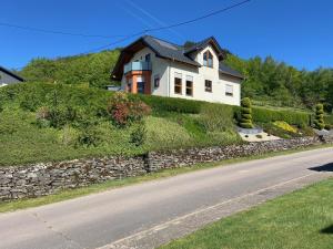 a white house on a hill with a stone wall at Ferienwohnung Hubertus in Irsch