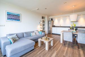 a living room with a blue couch and a kitchen at Appartementencomplex Juliana 164 in De Koog +2 photos