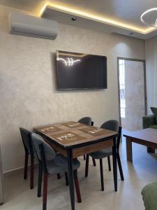a dining room table with chairs and a television on the wall at اقامة هبة 3 in Yebha
