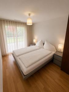 a bedroom with a large bed with white sheets and a window at Skender's Apartment in Interlaken