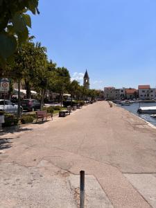 a sidewalk with benches next to a river with a clock tower at Katarina in Kaštela