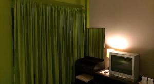 a room with a television and a green curtain at Baan Chomphu in Prachuap Khiri Khan