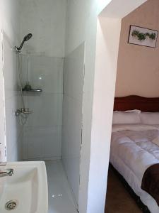 a bathroom with a shower and a bed and a sink at The Huts in Vila Praia Do Bilene +24 photos