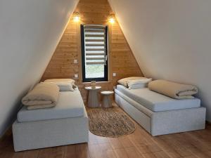 two beds in a attic room with a window at Áčko in Oščadnica