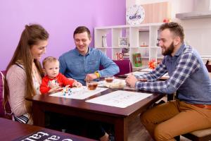 un grupo de personas sentadas en una mesa con un bebé en Gar'is Hostel Lviv, en Leópolis