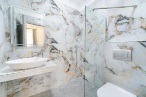 a white bathroom with a sink and a mirror at Studios Tasos Bi 2 in Chrysi Ammoudia