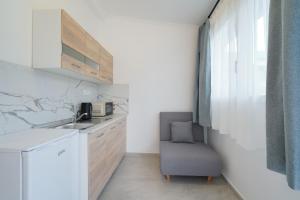 a small kitchen with a sink and a chair at Studios Tasos Bi 2 in Chrysi Ammoudia
