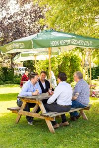 a group of people sitting at a picnic table under an umbrella at The George Inn in Lower Brailes