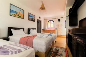 a bedroom with three beds and a window at Ifni Sunset in Sidi Ifni