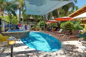 a swimming pool with chairs and umbrellas in a resort at Out of Africa Resort in Had Nes