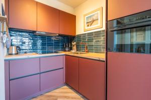 a kitchen with red and purple cabinets and a sink at Appartementencomplex Juliana 158 in De Koog