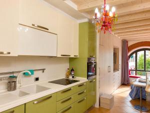 a kitchen with green and white cabinets and a chandelier at Corte del Centro Novate Milano in Novate Milanese
