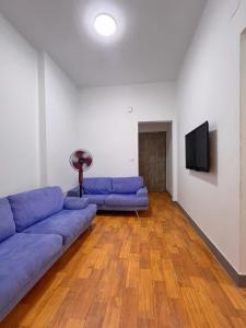 a living room with a blue couch and a flat screen tv at Nile & Museum Hideaway Haraka in Cairo