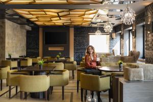 a woman sitting at a table in a restaurant at Tsarevets Boutique Hotel & SPA in Veliko Tŭrnovo