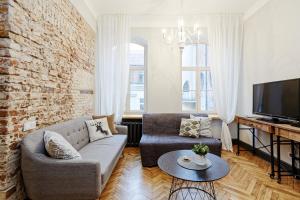 a living room with a couch and a tv at Riga Old Town Jāņa Sēta Residence in Riga