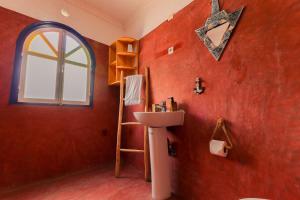 a bathroom with a red wall with a sink and a window at Ifni Sunset in Sidi Ifni +86 photos