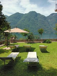 a group of picnic tables and an umbrella in the grass at Giardino sul lago, La Vigna in Nesso