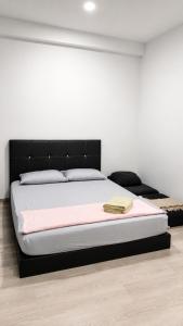 a bedroom with a bed with a black headboard at d 'ATHIF Homestay Samarahan 2 in Kuching