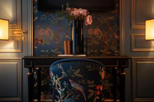 a room with a chair with a vase of flowers at Maison Proust, Hotel & Spa La Mer in Paris