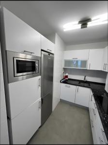 a kitchen with white cabinets and a stainless steel refrigerator at Comillas 30 Primera Línea de Playa in Comillas +14 photos