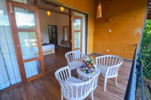 a porch with three chairs and a table with flowers on it at Amber Reach Cottages in Ella