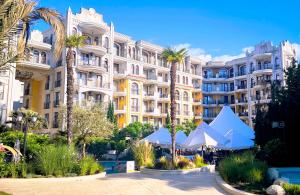 a large building with palm trees in front of it at Harmony Suites apartment 4 floor in Sunny Beach