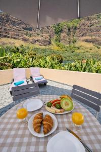 a table with plates of bread and fruit on it at Maresia's House, Madalena do Mar in Madalena do Mar