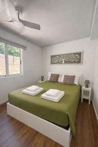 a white bedroom with a green bed with a window at Maresia's House, Madalena do Mar in Madalena do Mar
