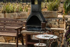 a outdoor grill and a bench next to a stone wall at עיינות ספיר - Einot Sapir in Sappir