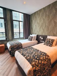 two beds in a hotel room with windows at Hotel Damsquare in Amsterdam