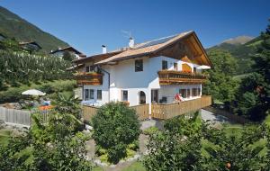 a large white house with a balcony and trees at Langeshof Fewo Abendrot in Caines