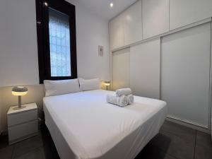 a bedroom with a white bed with two towels on it at Private Terrace House near Camp Nou in Hospitalet de Llobregat