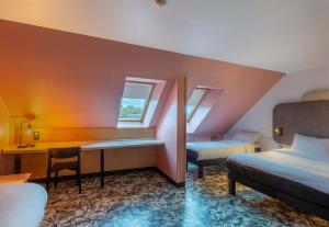 a hotel room with two beds and a desk at B&B HOTEL Chartres Centre Cathédrale 3 étoiles in Chartres