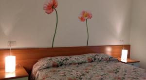 two flowers are on the wall above a bed at Green Village Accommodations in Colico