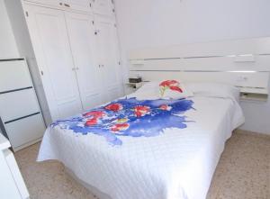 a bedroom with a white bed with a floral blanket at Brisa de la Laguna in Chipiona