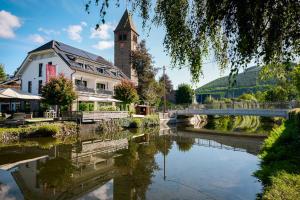 a building with a clock tower next to a river at Landhotel Voss im TalVital in Saalhausen