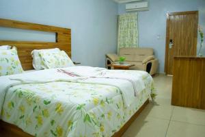 ein Schlafzimmer mit einem großen Bett und einem Stuhl in der Unterkunft Hôtel LEWI 2 Bouaké in Bouaké