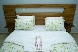 ein großes Bett mit weißen Laken und Kissen in der Unterkunft Hôtel LEWI 2 Bouaké in Bouaké + 3 Fotos