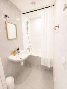 a white bathroom with a sink and a shower at Le Lac Bleu - Sevrier in Sévrier
