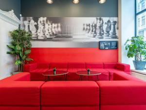 a red couch in a restaurant with two tables at Ibis Riga Centre in Riga